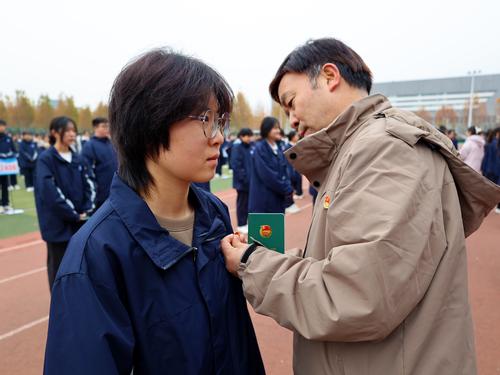 4班主任老师李德义为新团员学生佩戴团徽